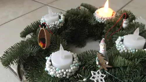 Adventskranz mit brennenden Kerzen und festlicher Dekoration.