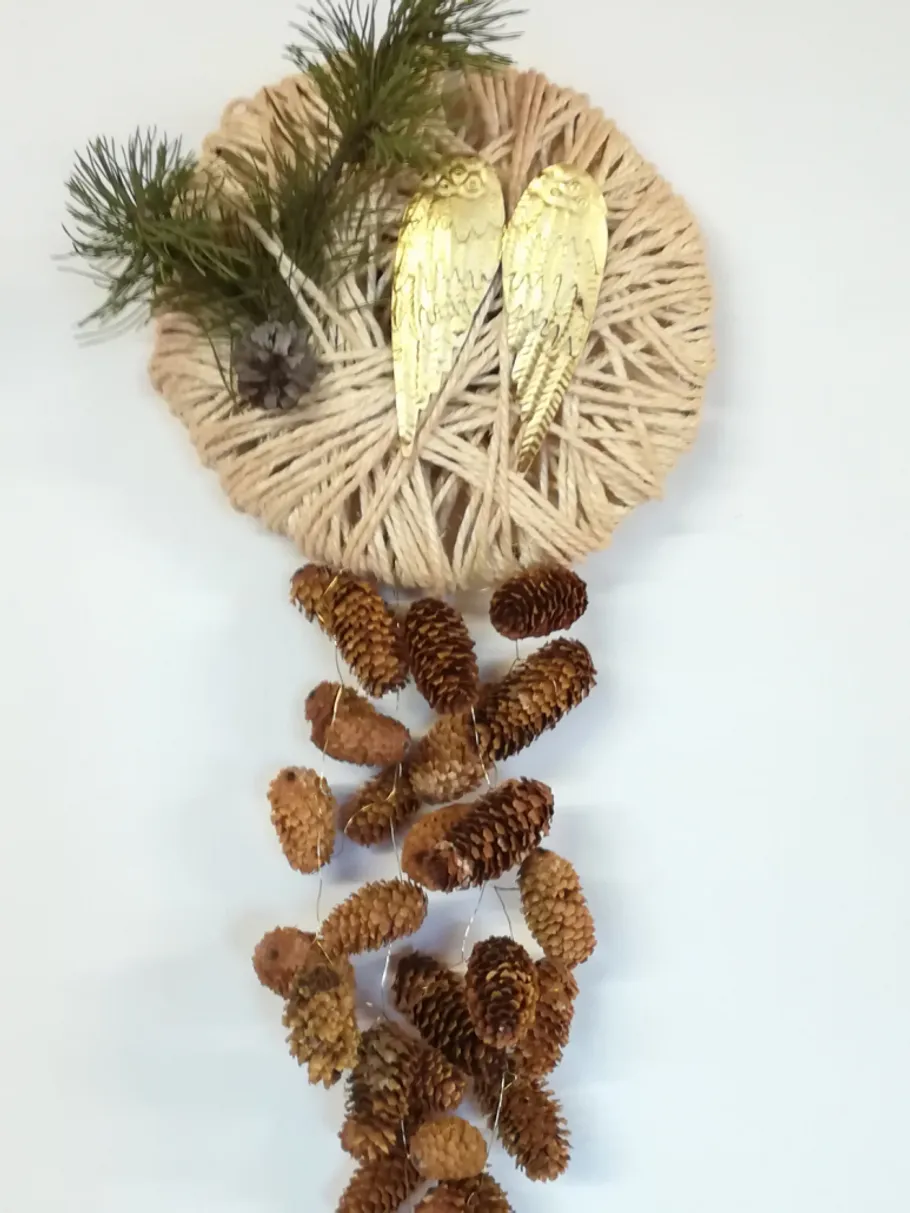 Wanddeko aus Kieferzapfen, geflochten, mit goldenen Engelsflügeln.