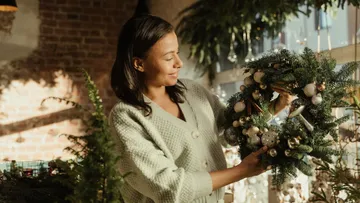 Woman holding a decorative Christmas wreath in a shop.