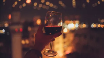 A drink in hand, surrounded by evening lights.