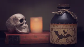 A bottle of “bat wing potion” next to a skull.