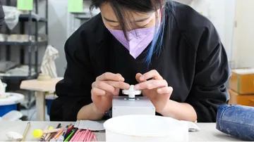 A person concentrates on a machine in a studio.