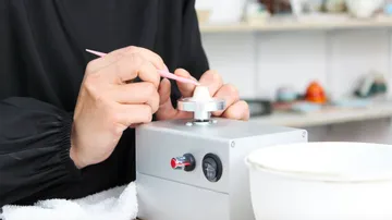 Händed bei der Arbeit mit einem Werkzeug an einem Objekt.