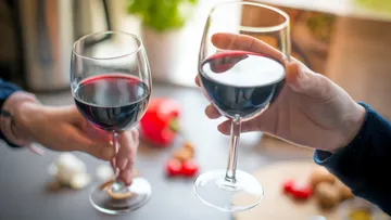 Two wine glasses are held while toasting, cheerful context.