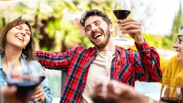 Menschen heben Gläser, feiern und lachen in entspannter Umgebung.