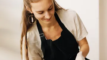 Junge Frau lächelt, während sie etwas in der Hand formt.