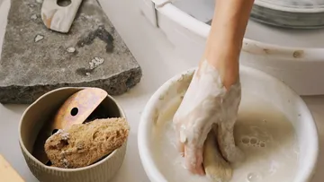Hand taucht in Schüssel mit Flüssigkeit, um zu reinigen.