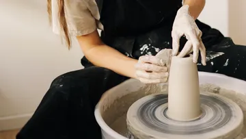 Töpfer formt einen Becher auf einer Töpferscheibe.