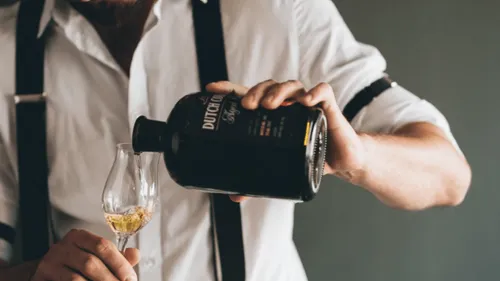 A man pours a drink into a glass.