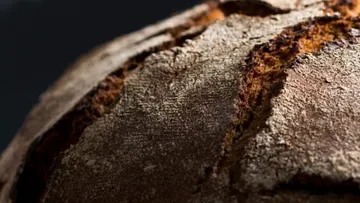Rustic bread with a crispy crust on a dark background.