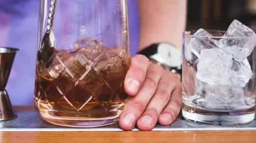 A glass of ice is placed next to a carafe with drink.