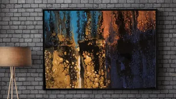 Abstract painting hanging on a brick wall, bright colors.