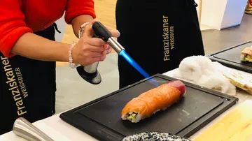Koch verwendet einen Brenner, um Sushi zu flambieren.