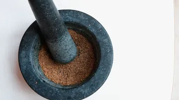 Mortar with crushed ingredients on a bright surface.