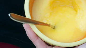 Löffel rührt in gelber, cremiger Masse in Schüssel.
