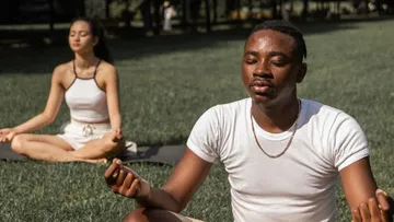 Two people are relaxing in a meadow and meditating.
