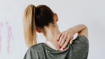 Woman touches her neck as she turns around.