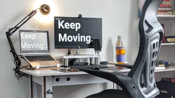 Desk with monitors that say “Keep Moving.”