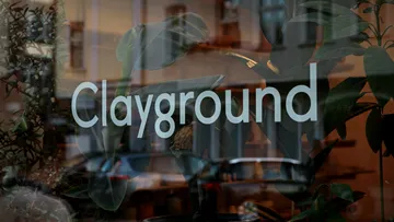 Fensterschild zeigt `Clayground`, umgeben von Pflanzen.