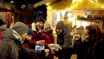Gruppe von Menschen, die auf einem festlichen Jahrmarkt anstoßen.