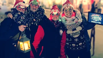 Vier Personen in festlichen Outfits halten eine Laterne.