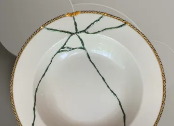 Zerbrochene Schüssel, mit grünen und goldenen Reparaturfäden.