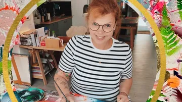 Frau mit Pinsel malt in einem kreativen Raum.