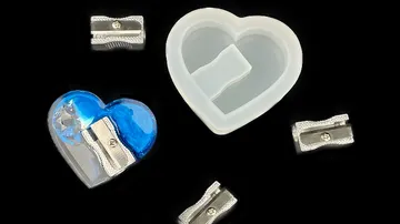 A heart-shaped sharpener is placed around a transparent sharpener.