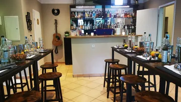 Bar with tables and chairs, drinks provided.