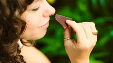 Woman keeps chocolate and enjoys it in nature.