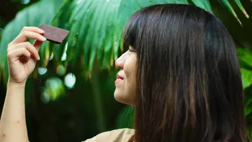 A woman is holding chocolate in a green environment.