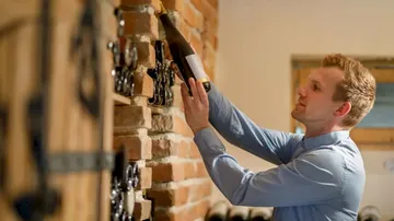A man pulls a bottle of wine out of a wall.
