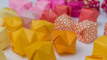 Bunte Origami-Formen liegen verstreut auf einem Tisch.