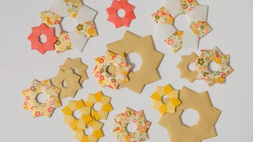 Bunte Papercrafts in Blumenform auf einem weißen Hintergrund.