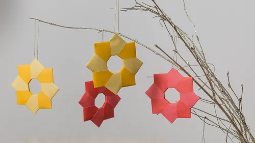 Paper stars hang on a branch against a grey background.