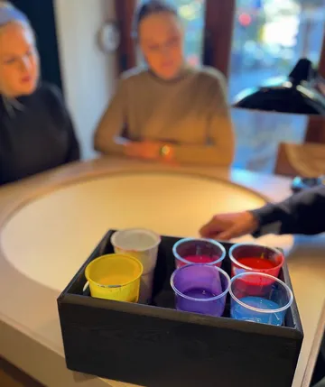 Paint cups on table with blurred background.