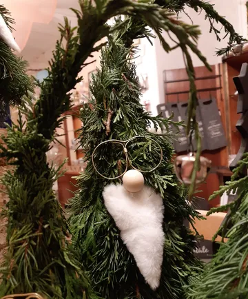 Grüner Tannenbaum mit einer Figur und Dekorationen im Hintergrund.