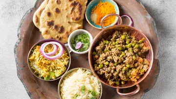 Indisches Gericht mit Curry, Reis, Naan, Gewürzen und Beilagen.