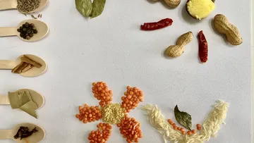 Spices and legumes form a flower shape on the table.