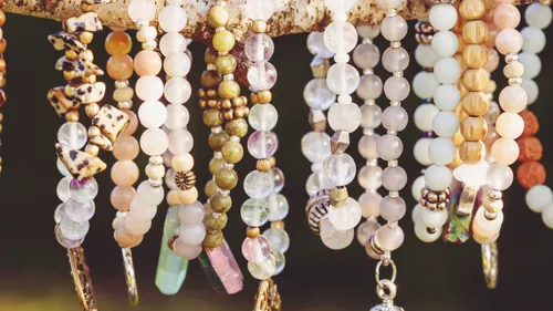 Necklaces of pearls hang from a branch in natural light.