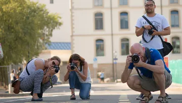 Vier Fotografen knien auf der Straße und fotografieren.