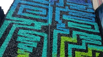 Colourful wall mural with geometric patterns in an urban setting.