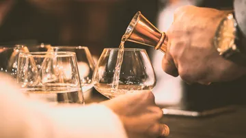 A glass is filled with liquid from a measuring cup.