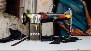 Sewing machine sews pieces of fabric in a simple workshop.