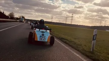 Dreirädrige Fahrzeuge fahren auf einer Landstraße bei Sonnenuntergang.