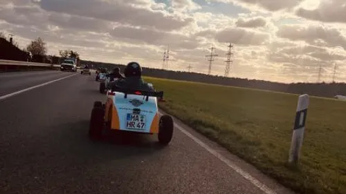 Dreirädrige Fahrzeuge fahren auf einer Landstraße bei Sonnenuntergang.