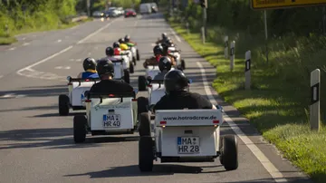 Kleine Fahrzeuge fahren auf einer Straße in einer Gruppe.