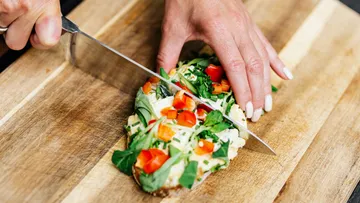A piece of bread is cut with a knife to portion it.