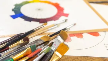 Brushes lie chaotically on a table with a color palette.