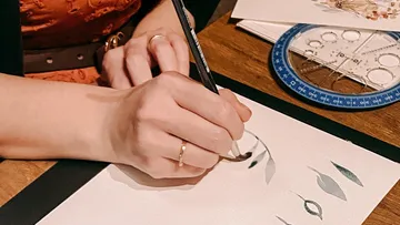 Eine Hand malt mit einem Stift auf Zeichenpapier.